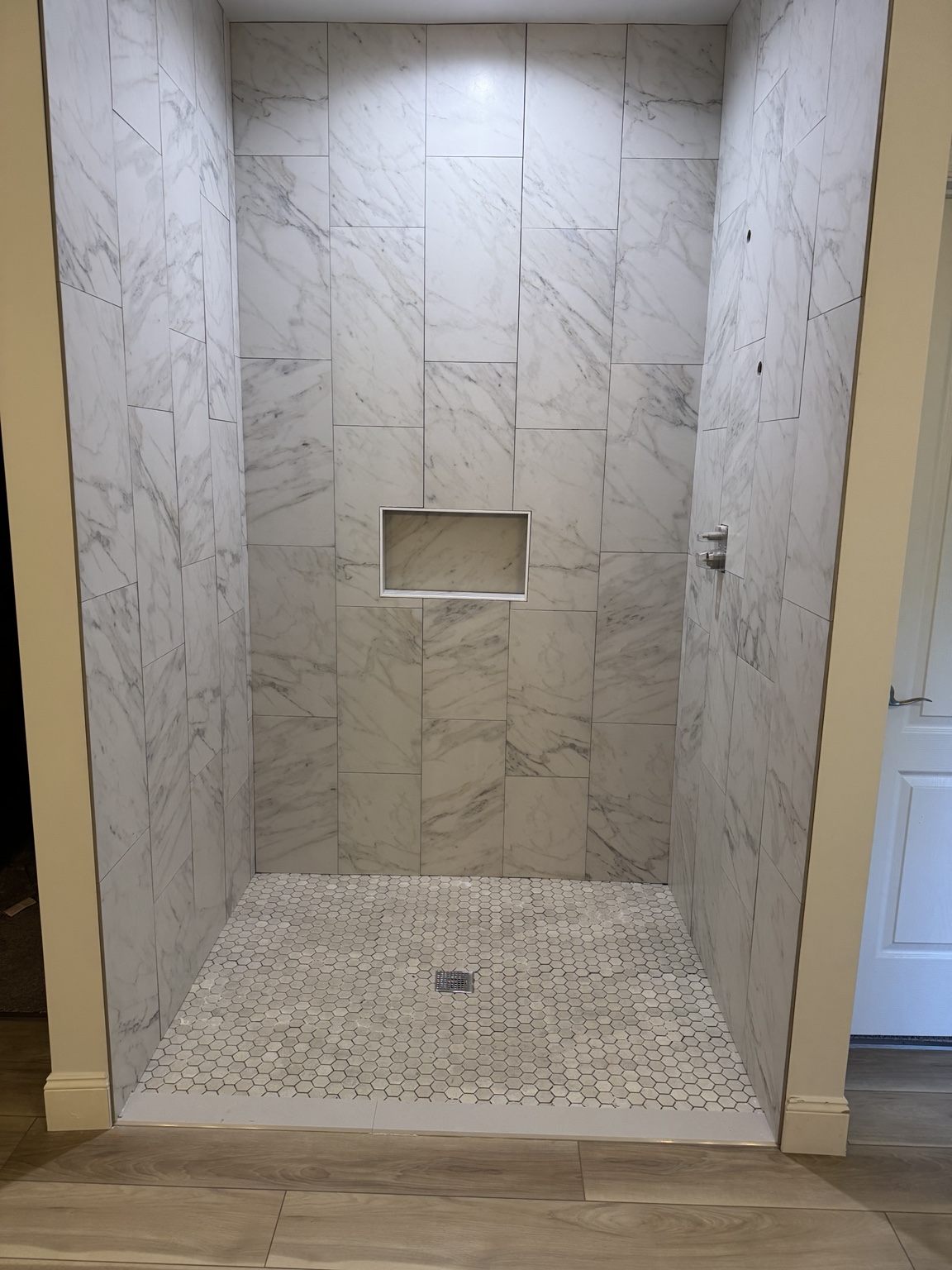 Walk-in shower finished with large marble-look wall tile