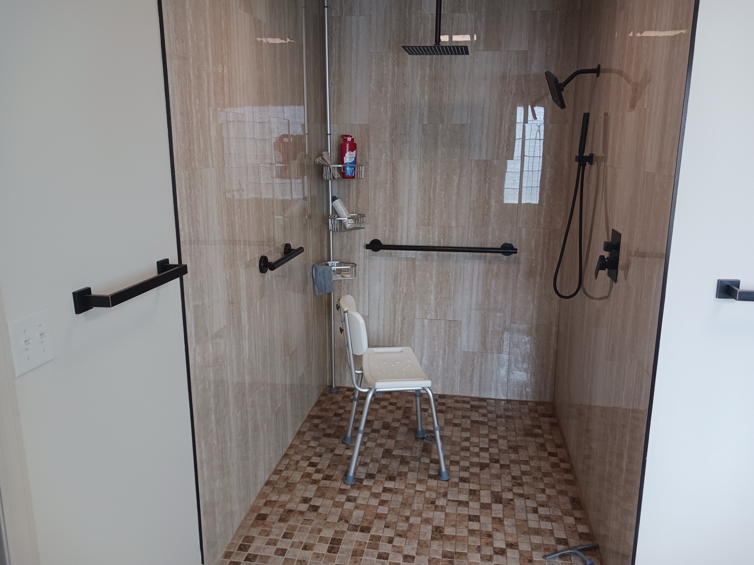 Large curbless walk-in shower with bench and handheld shower fixtures